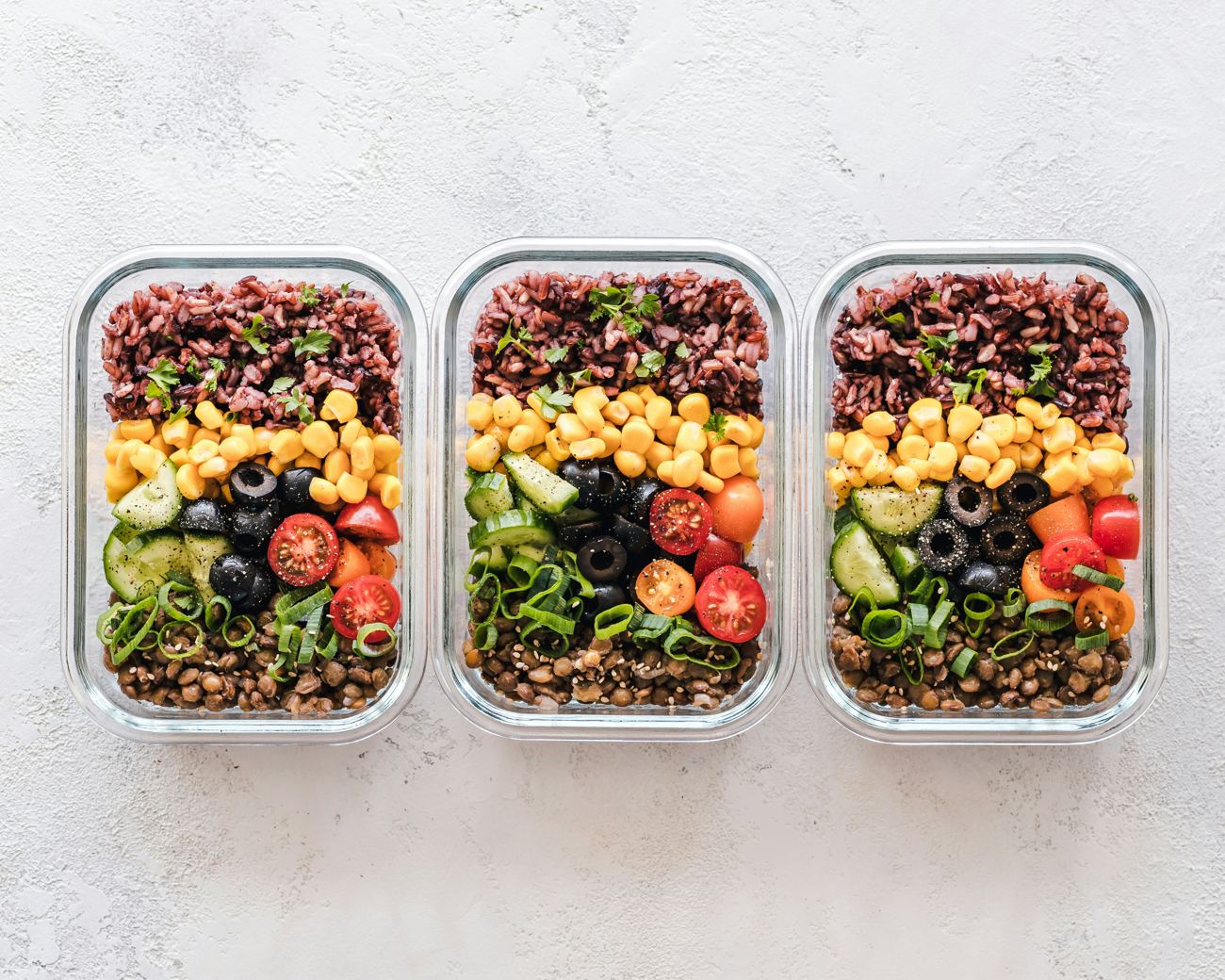 Healthy meal prep containers with rice, lentils and vegetables